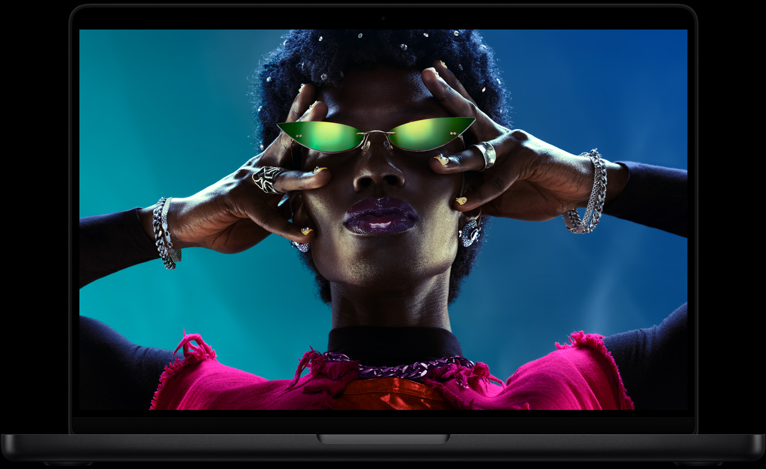 شاشة MacBook Pro ملونة تعرض شخصاً يرتدي نظارات شمسية، ما يبرز ألوان شاشة ريتنا ليكويد XDR النابضة بالحياة