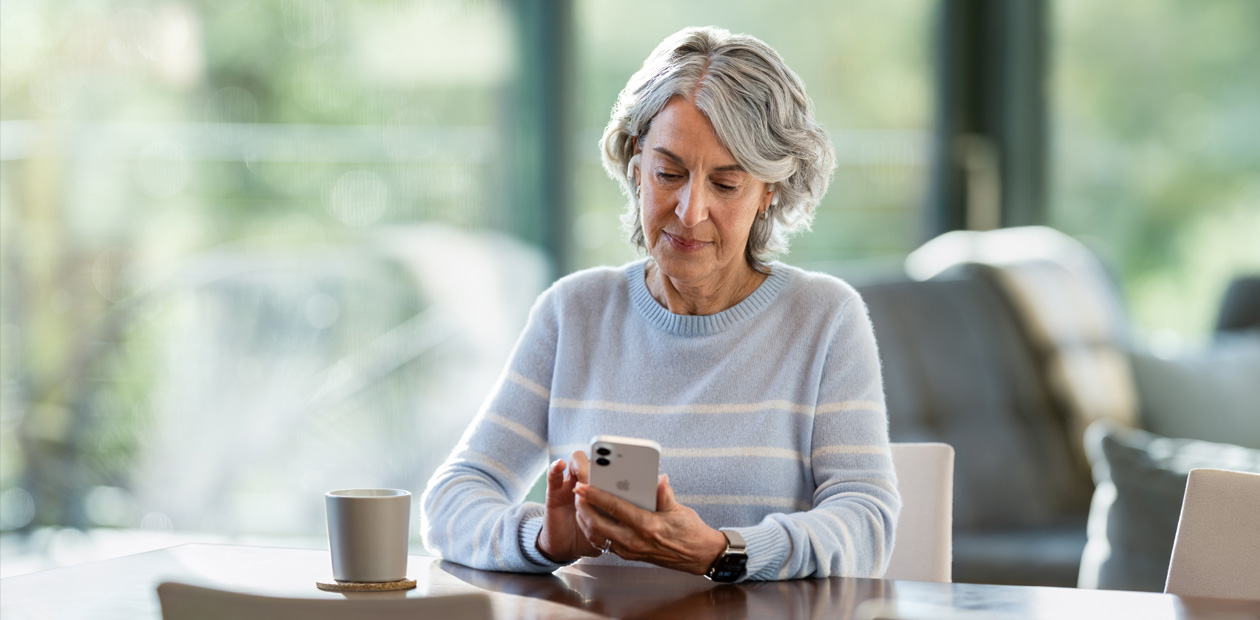 テーブルでiPhoneを見ている年配の女性